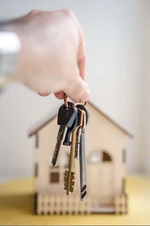 Photo of house keys with scale model house in the back