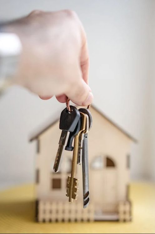 Photo of house keys with scale model house in the back