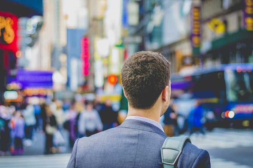 Photo of a man on suit walking on a busy street