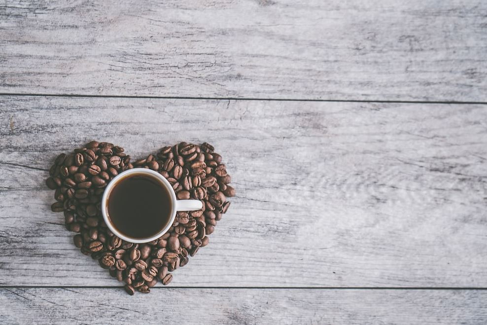 Photo of a cup of coffee on top of heart-shaped coffee beans