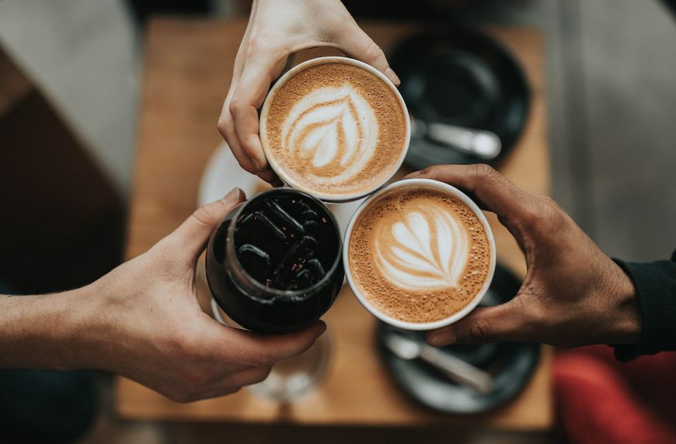 Photo of 3 people holding a coffee with latte art