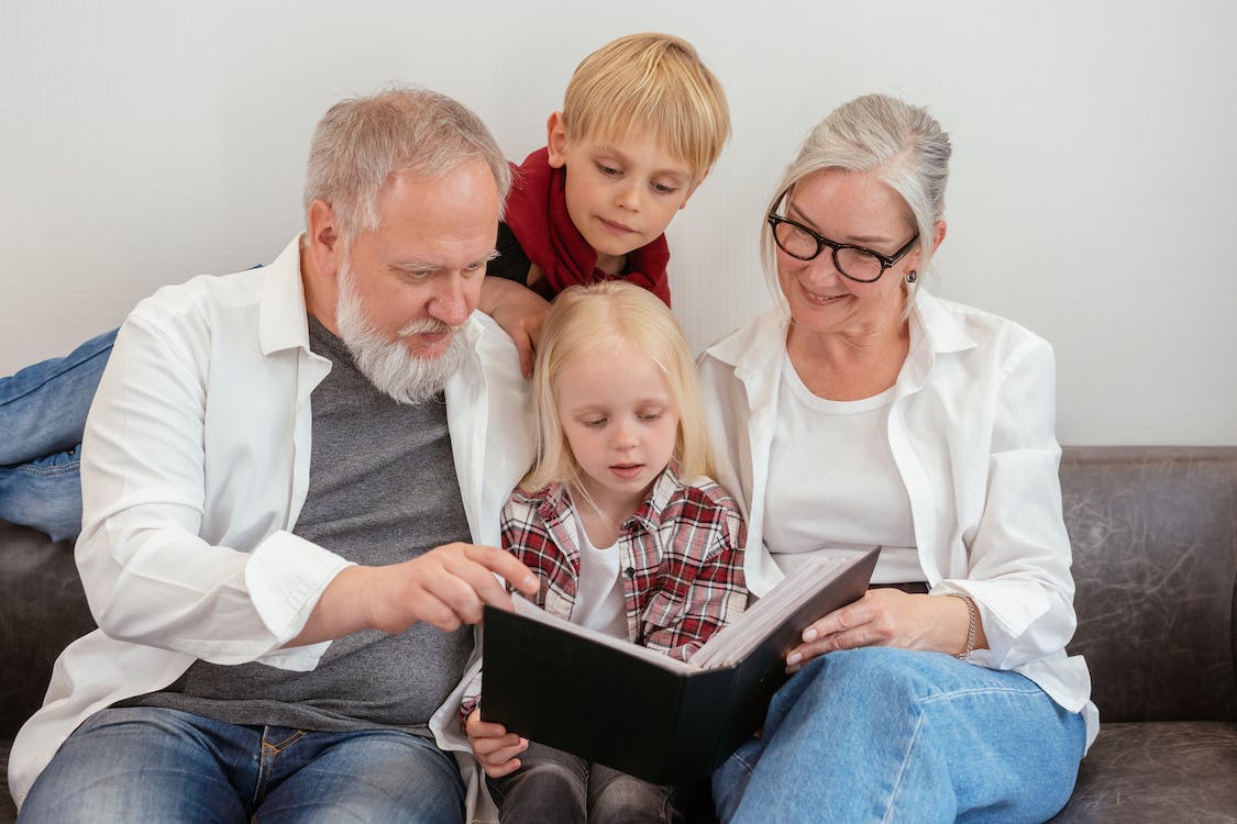 Photo of grandparents reading a book with their grandchildren