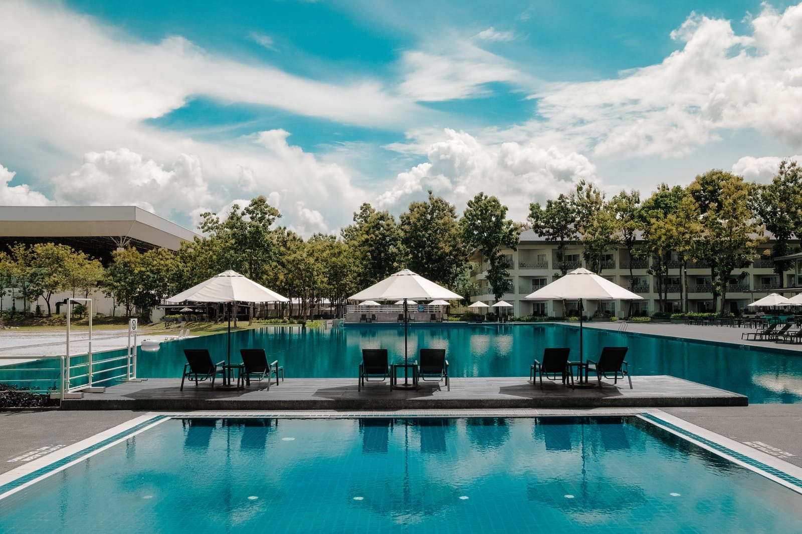 Photo of a swimming pool with three umbrellas standing on the isle