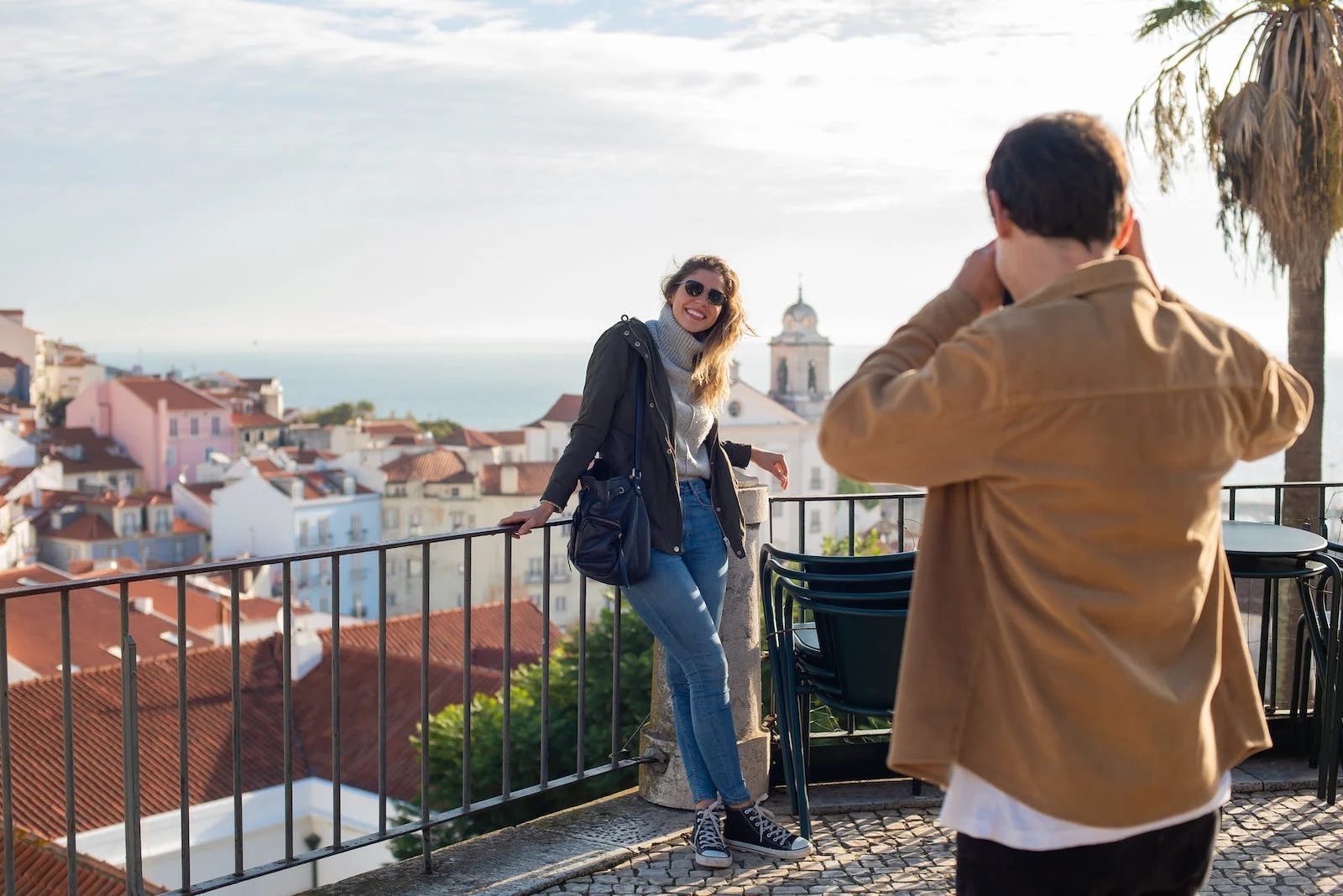 Photo of a guy taking pictures of a girl with the city view on the background