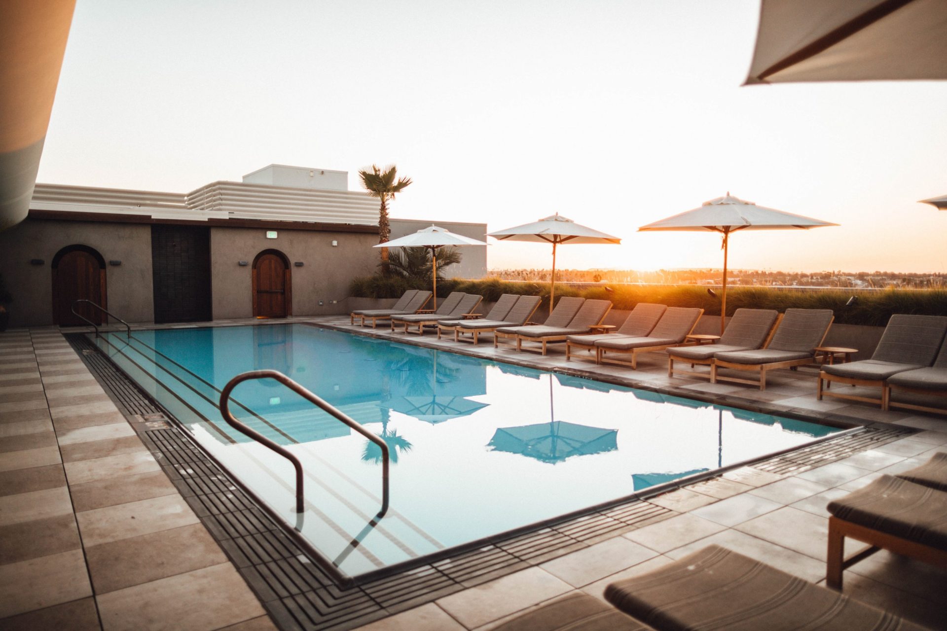 Rooftop in-ground swimming pool on a sunset backdrop.