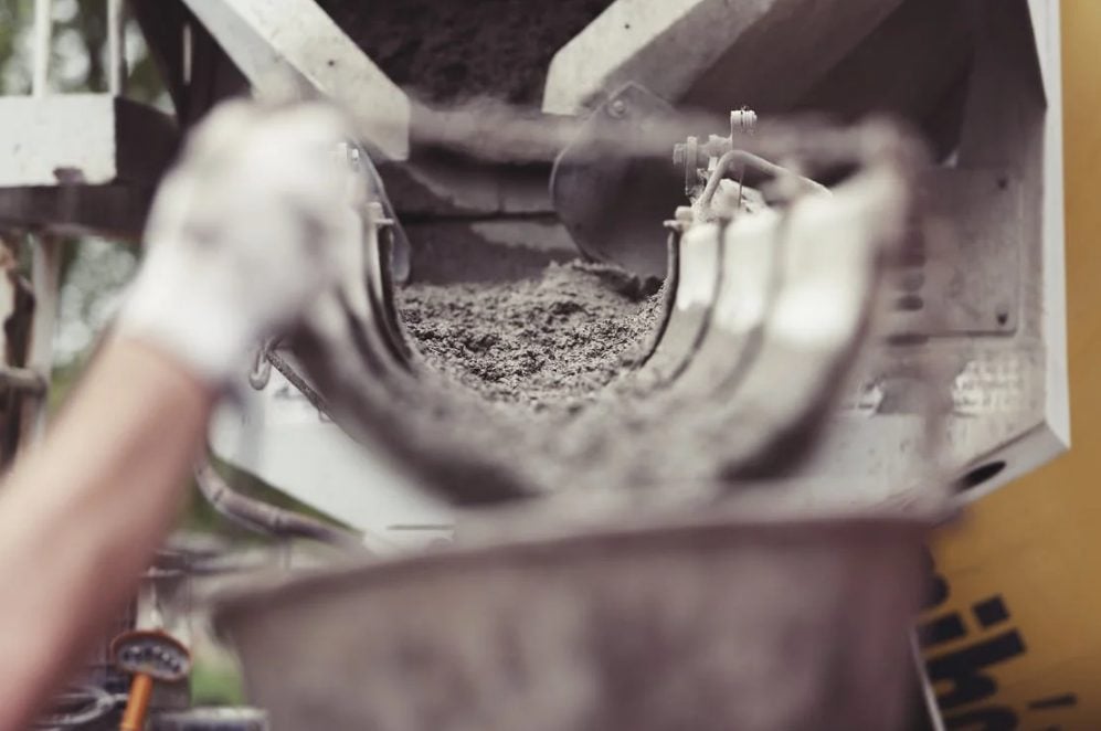 A hand wearing work gloves is carrying a bucket