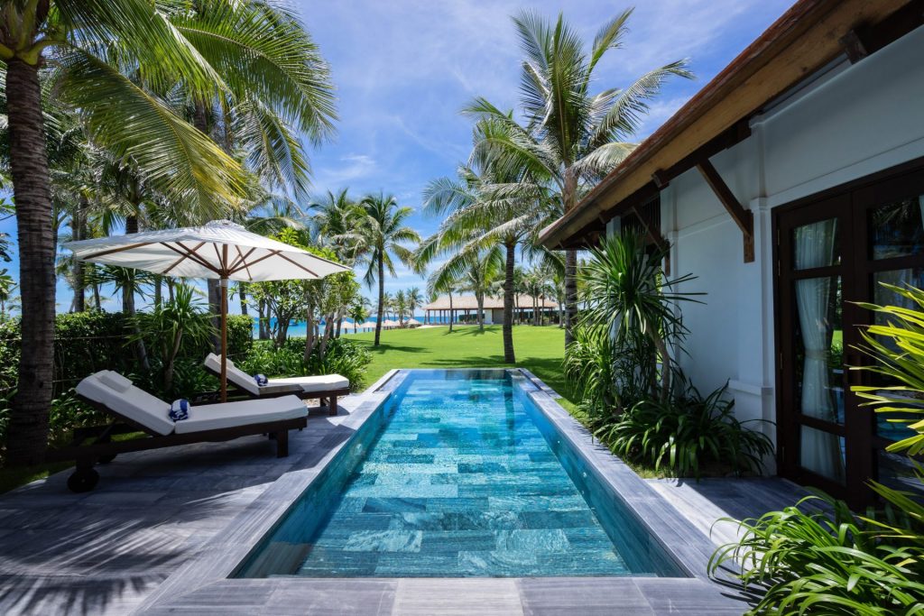 Beachfront swimming pool surrounded by palm trees