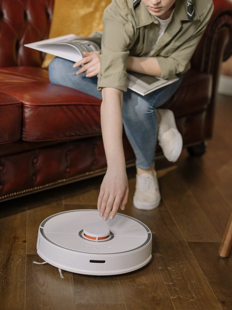 Woman in Blue Denim Jeans Sitting on Brown Leather Couch Home Cleaning Device