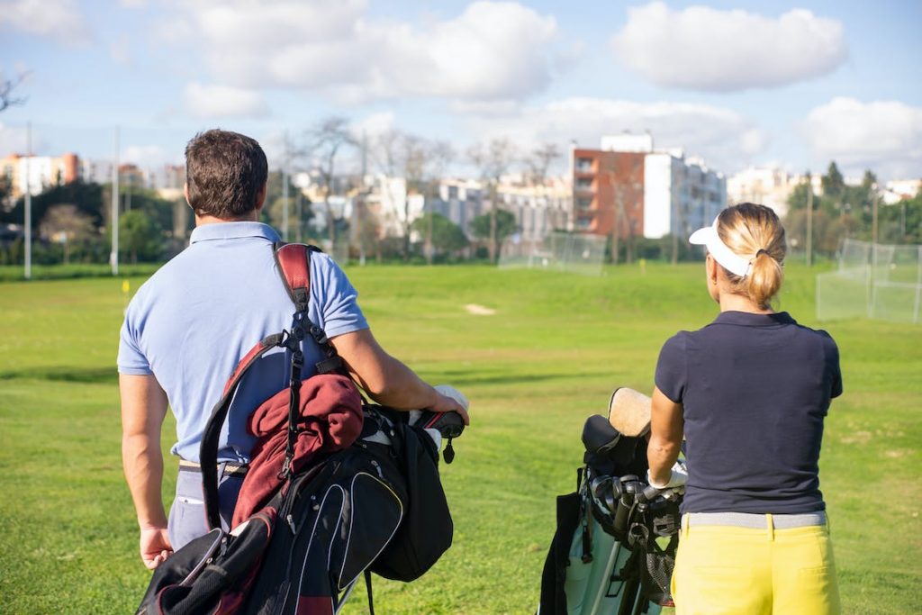Man and Woman Carrying Golf Equipment photo by Kampus Production from Pexels