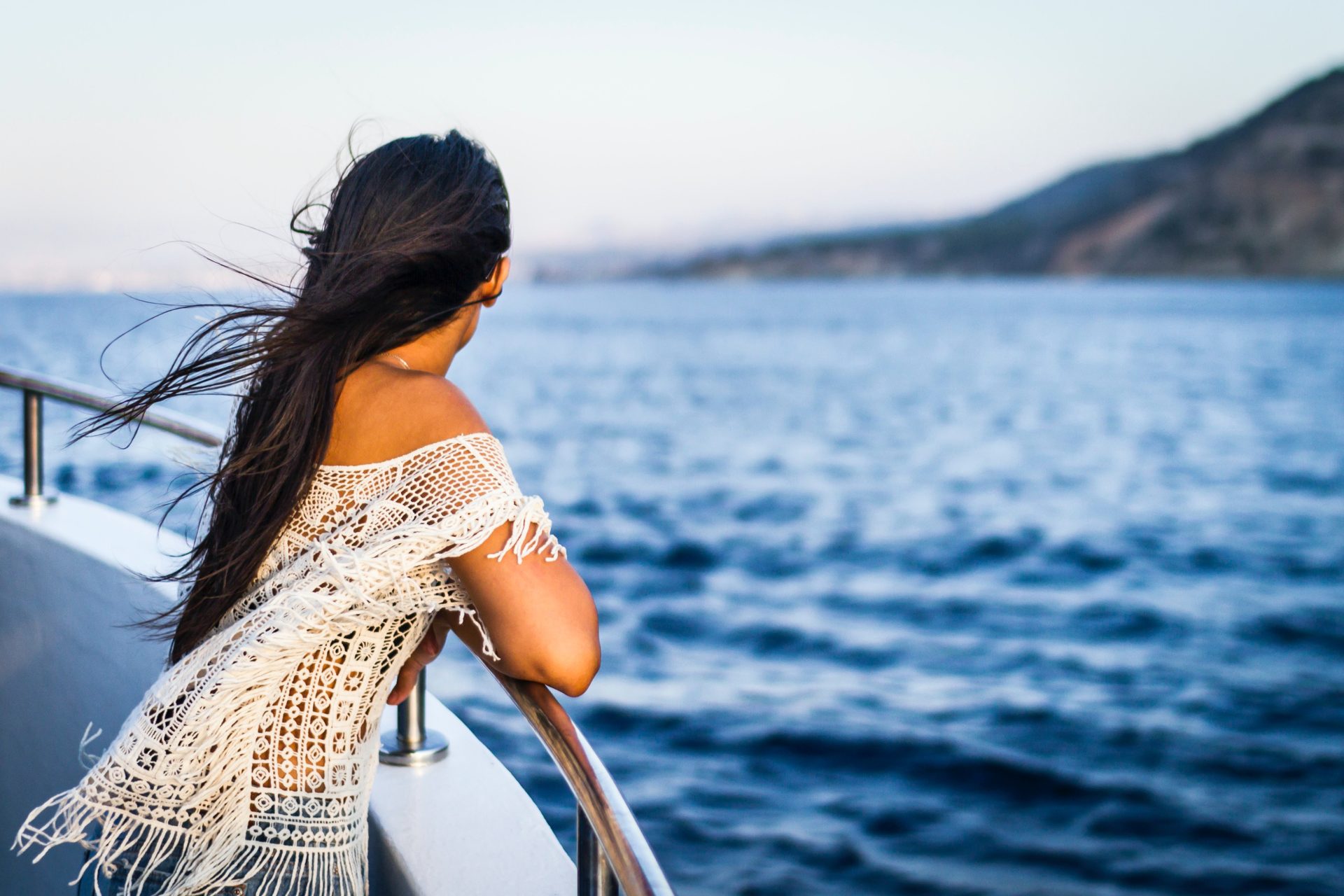 Woman staring at the ocean while standing on deck. 