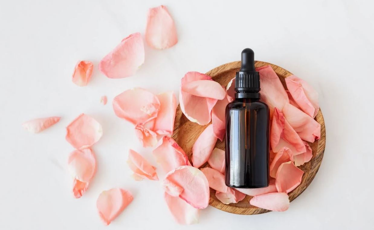 Flat lay photo of a frangrance oil in a bottle with scattered petals