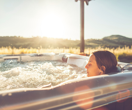 Woman in whirlpool hot tub at sunset