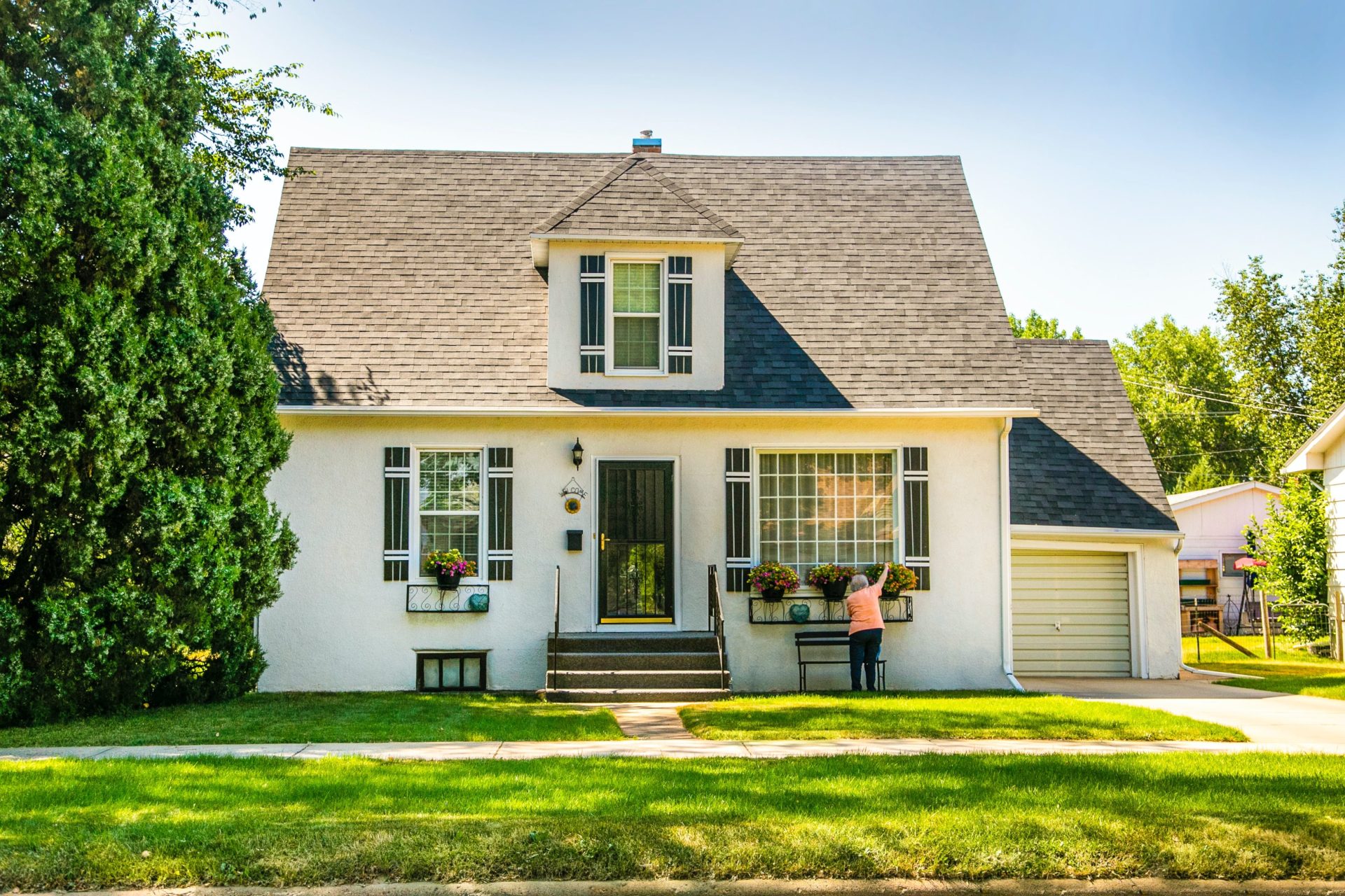 A white old-fashoned house surrounded by trees and lit by the afternoon sun. 